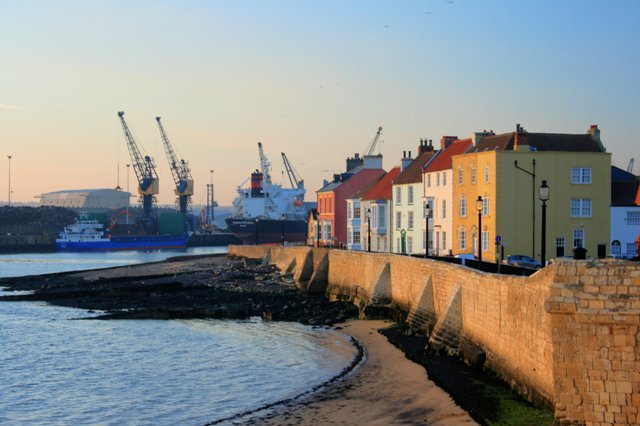 Town Wall, Hartlepool, Durham, England. Dating from the late 14th century the limestone wall once enclosed the whole of the medieval town. The terraced houses overlook the entrance to Victoria Docks in the background.